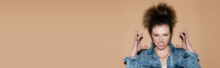 Aggressive model in denim jacket looking at camera on beige background, bannerの写真素材