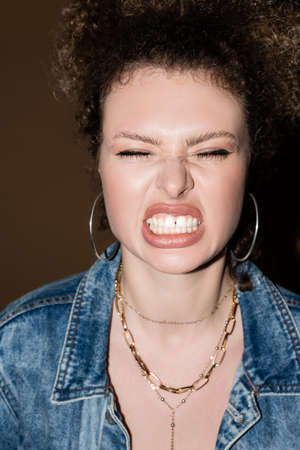 Angry model in denim jacket and accessories showing teeth on black backgroundの写真素材