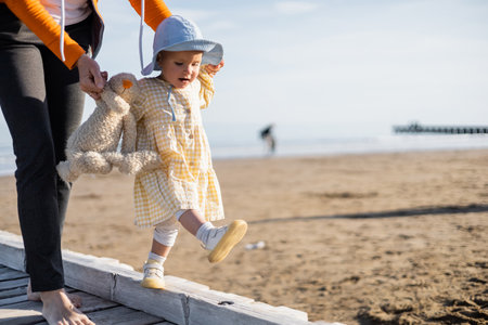 Baby girl walking near mother on pier on beach in Trevisoの写真素材