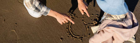 Cropped view of father drawing heart sign on sand near daughter, bannerの写真素材