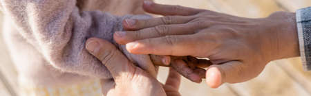 Cropped view of father holding hand of daughter in sand on beach, bannerの写真素材