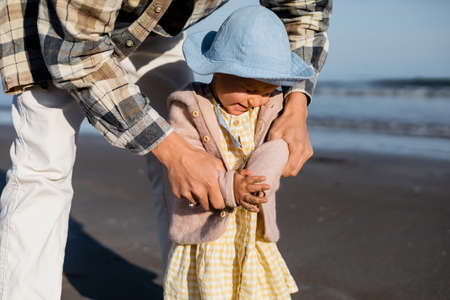 Dad holding cheerful baby daughter on beachの写真素材