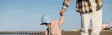 Father holding hand of baby daughter on beach in Treviso, bannerの写真素材