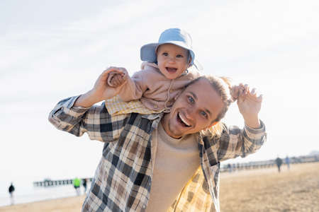Happy man and daughter looking at camera on beach in Italyの写真素材