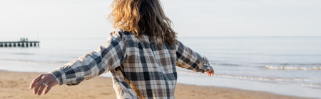 Back view of long haired man in shirt walking on beach near adriatic sea in Italy, bannerの写真素材