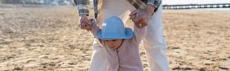 Man holding hands of baby on beach, bannerの写真素材