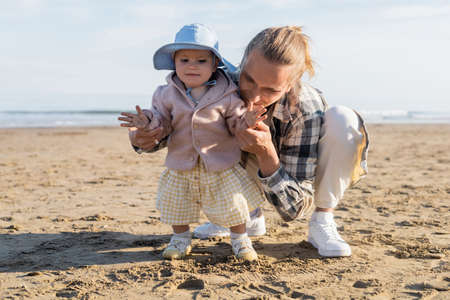 Young father holding hand of baby child on sandy beach in Treviso