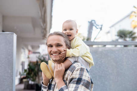 Happy baby and father looking at camera on urban streetの写真素材