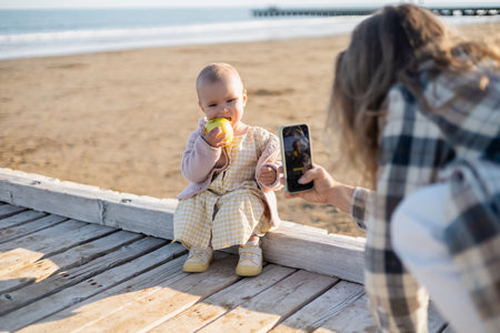Blurred father taking photo of baby with apple on wooden pier in Italyの写真素材