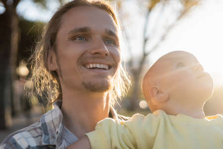 Cheerful man looking away near baby girl outdoorsの写真素材