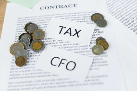 papers with tax and cfo lettering on contract with coinsの写真素材