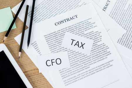 top view of papers with tax and cfo lettering near contract and digital tablet on deskの写真素材