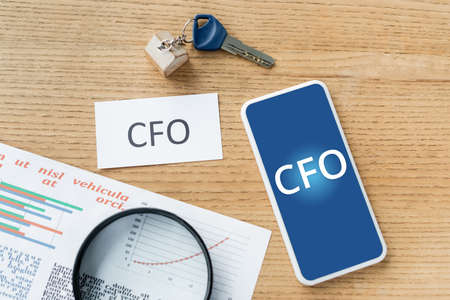top view of magnifier near charts, paper with cfo lettering near smartphone cfo lettering on screenの写真素材