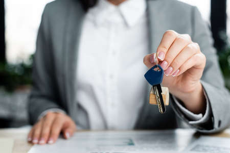 cropped view of businesswoman holding key with key chainの写真素材