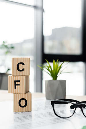 cubes with cfo letters near glasses and document on deskの写真素材