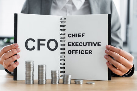 stacked silver coins near woman holding notebook with cfo and chief executive officer letteringの写真素材