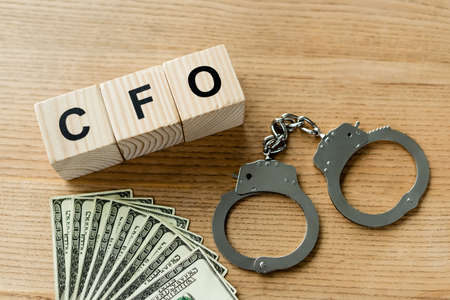 top view of wooden cubes with cfo letters near handcuffs and money on deskの写真素材
