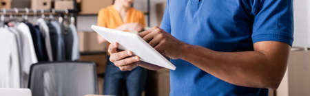 Cropped view of african american courier using digital tablet in online web store, bannerの写真素材