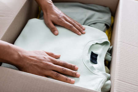 Cropped view of african american seller putting clothes in package in online web storeの写真素材