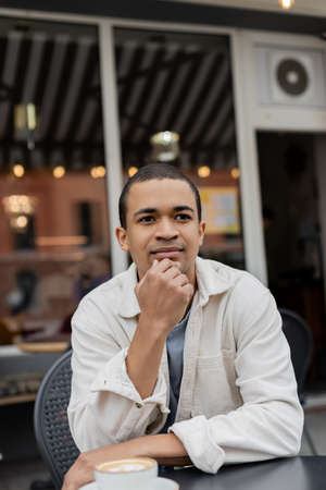 portrait of pensive african american man sitting on summer terraceの写真素材