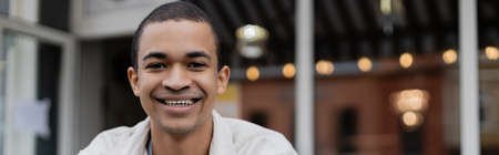 smiling and young african american man looking at camera outside, bannerの写真素材
