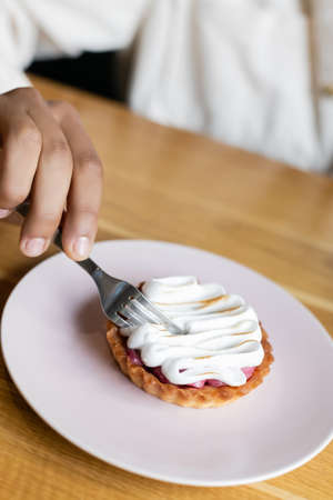 partial view of african american man holding fork near tasty tart on plate