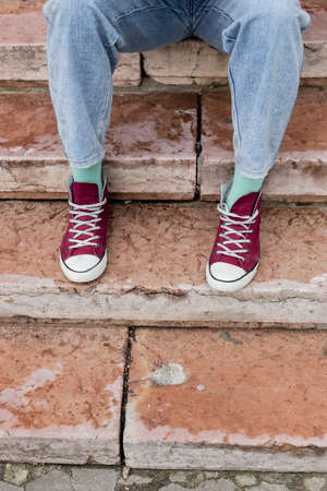 cropped view of man in jeans and sneakers sitting on stairsの写真素材