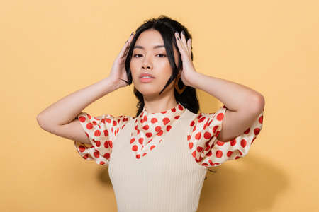 Fashionable asian model looking at camera on orange backgroundの写真素材