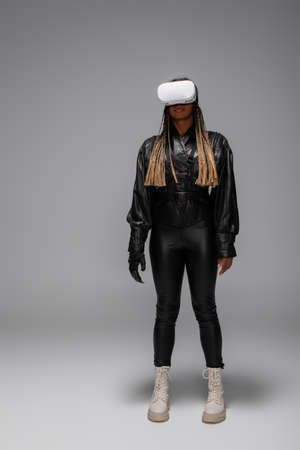 African american woman in cyber glove and vr headset on grey backgroundの写真素材