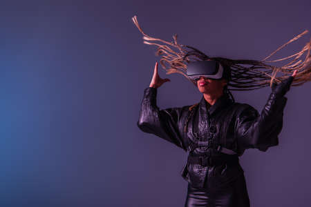 African american woman with pigtails gaming in vr headset on blue and purple backgroundの写真素材