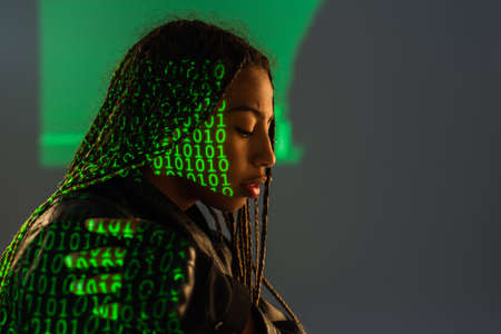 Side view of african american woman with projection of binary code on grey backgroundの写真素材