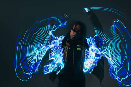 Stylish african american woman in smart glasses posing near neon lights on grey backgroundの写真素材