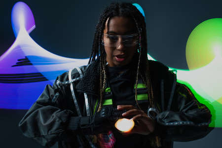 Stylish african american woman in smart glasses standing near abstraction on grey backgroundの写真素材