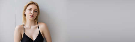 Young blonde woman in dress looking at camera at home, bannerの写真素材