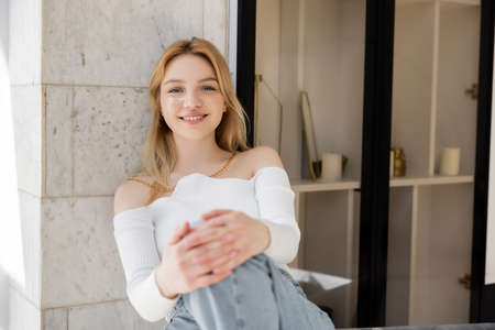 Happy young woman with glitter makeup looking at camera at homeの写真素材
