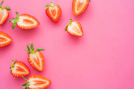Flat lay with halves of strawberries on pink backgroundの写真素材