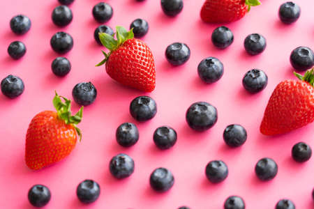 Close up view of juicy strawberries and blueberries on pink backgroundの写真素材