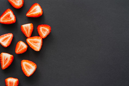 Top view of juicy cut berries on black background with copy space