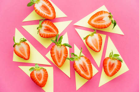 Flat lay of strawberries on yellow triangles on pink backgroundの写真素材