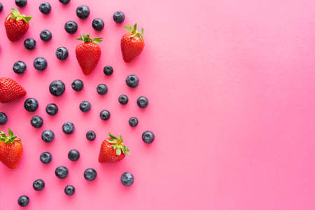 Flat lay with blueberries and strawberries on pink surfaceの写真素材