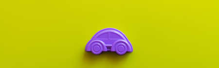 top view of violet plastic car on bright yellow background, banner