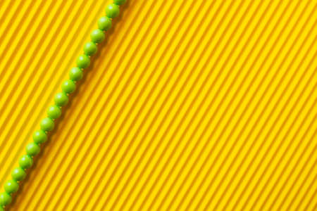 top view of line of green balls on yellow striped backgroundの写真素材
