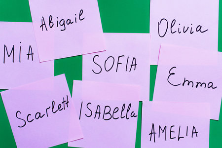 top view of pale purple cards with female names on green background