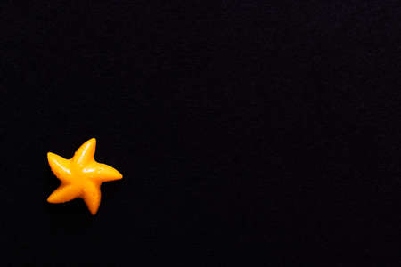 top view of bright yellow mold in shape of starfish isolated on blackの写真素材