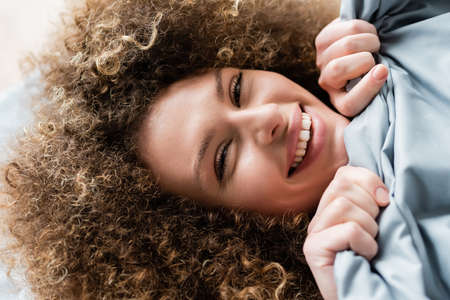 top view of joyful woman with blanket smiling at cameraの写真素材