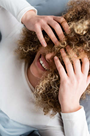 top view of smiling woman obscuring face with curly hairの写真素材