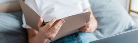 partial view of woman holding folder while working at home, banner