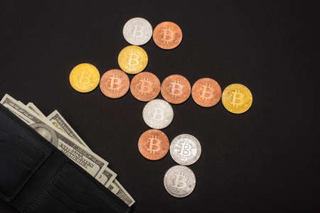 KYIV, UKRAINE - APRIL 26, 2022: Top view of bitcoins and wallet with money isolated on blackのeditorial素材