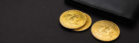KYIV, UKRAINE - APRIL 26, 2022: Close up view of wallet and golden bitcoins on black background, bannerのeditorial素材