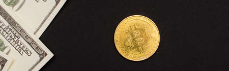 KYIV, UKRAINE - APRIL 26, 2022: Top view of dollar banknotes and golden bitcoin isolated on black, bannerのeditorial素材